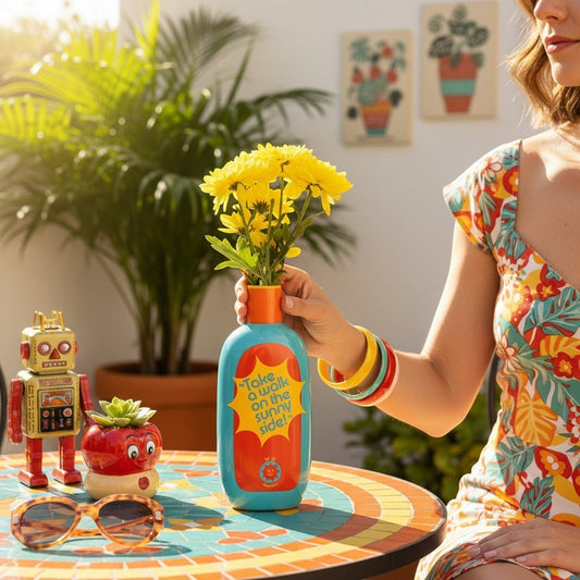 Jarrón cerámico Protector Solar de Ban.do en Retrópica Tienda, azul con diseño retro y flores amarillas en una mesa.